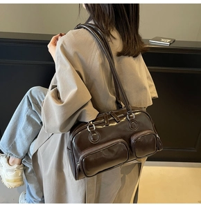 Side view of chocolate brown glossy leather shoulder bag worn over a trench coat