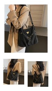 Detail view of large black commuter shoulder bag with gold metal triangular plate