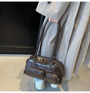 Detail of dark brown glossy patent leather shoulder bag with multiple functional zip pockets
