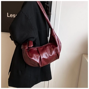 Detail shot of the burgundy pleats and glossy finish on this vintage crescent shoulder bag