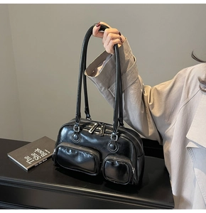 Detail of black glossy leather bowling bag with functional double front zipper pockets