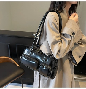 Detail of black glossy leather bowling bag featuring dual front pockets and silver hardware