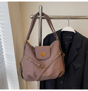 Detail of taupe synthetic leather tote with metal triangle plaque and buckle strap