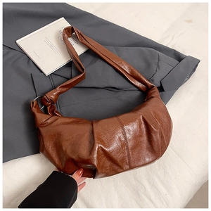 Detail of deep brown croissant bag featuring pleated PU leather and knotted shoulder strap