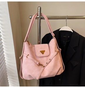 Detailed close-up of pink suede tote bag featuring a golden metal logo plaque and hardware