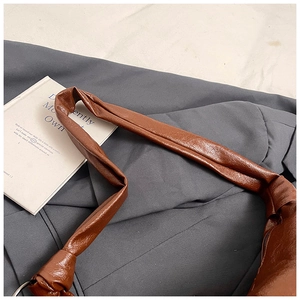 Detail of brown leather strap with knot design and metal ring on large crossbody bag