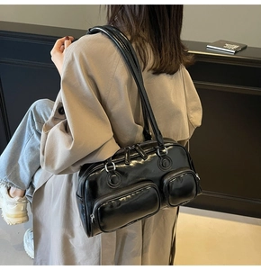 Side view of black glossy shoulder bag with multiple functional utility pockets and slim straps