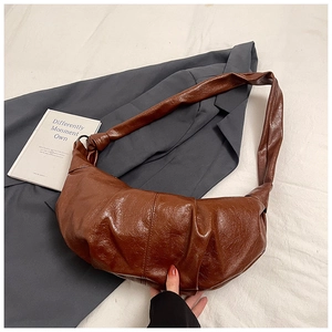 Detail of vintage brown pleated leather dumpling bag on minimalist fabric background