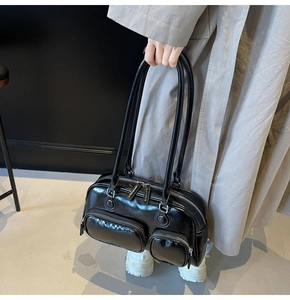 Detail of vintage black patent leather shoulder bag featuring dual front zipper pockets