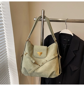 Detail of pea green matte leather shoulder bag featuring triangle metal logo and gold hardware