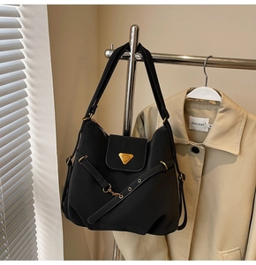Detail of black nylon shoulder bag with golden hardware and signature metal logo