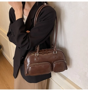 Macro detail of vintage brown shoulder bag showing polished leather texture and front zippers