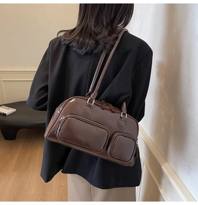 Detailed view of dark brown glossy leather shoulder bag with two front zipper pockets