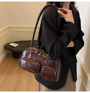 Close-up of a burgundy glossy shoulder bag featuring multiple pockets and silver zippers