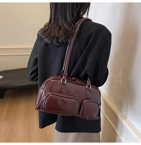 Detail of burgundy glossy patent leather shoulder bag with two front zipper pockets
