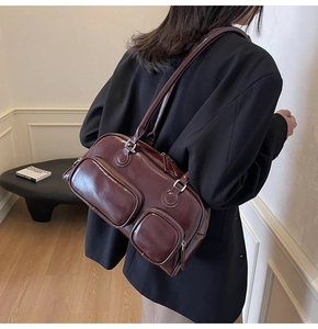 Deep burgundy bowling bag with double zipper pockets shown on model with black jacket
