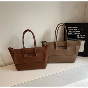 Close-up of litchi texture on brown and coffee leather tote bags on marble surface
