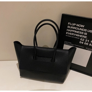 Detail of black pebbled leather tote bag with large flap closure and dual handles