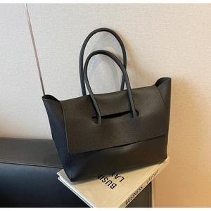 Detailed macro view of black lychee grain leather texture on high capacity tote bag