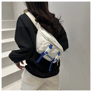 Détail du sac bandoulière en nylon blanc avec sangle bleue et inscription FASHIONBAG