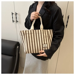 Detailed close-up of brown and white striped canvas tote bag with a camping woven label