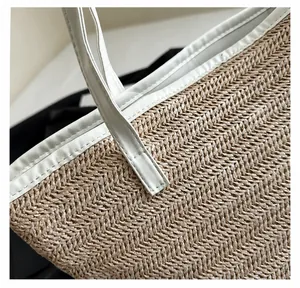 Détail de la couture du sac cabas en paille beige avec anse et bordure en cuir blanc