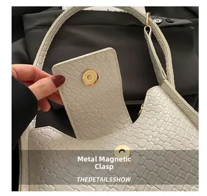 Détail du sac tressé blanc avec un fermoir magnétique rond en métal doré élégant