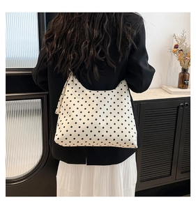 Vista posteriore di una modella con una grande borsa tote in tela a pois neri per il relax