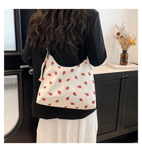 Dettaglio della borsa tote bianca in tela con stampa fragole indossata da modella