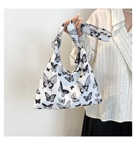 Dettaglio della borsa hobo in tela bianca con stampe di farfalle nere e fibbia in metallo