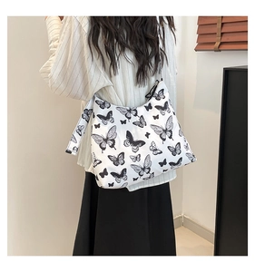 Vista dettagliata della borsa tote in tela con stampe di farfalle nere e tracolla larga