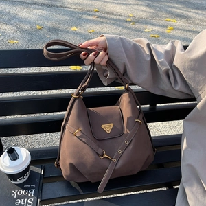 Brown vintage faux leather tote bag with gold triangle plaque on wooden bench