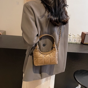 Sac bandoulière matelassé avec chaîne et poignée dans un décor intérieur épuré