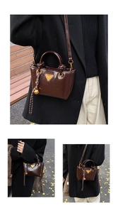 Gros plan sur un sac cabas marron brillant avec logo triangle doré et pendentif tressé