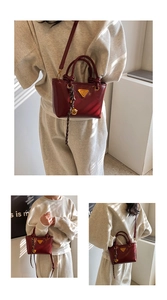 Détail du sac cabas en cuir verni bordeaux avec logo triangle et breloque tressée
