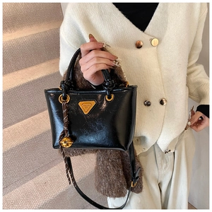 Détail d'un sac cabas en cuir verni noir avec logo doré et pendentif clochette