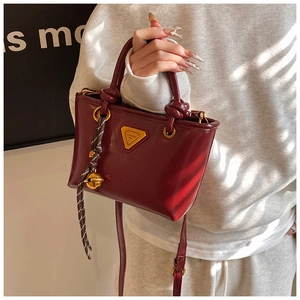 Détail d'un mini sac cabas rouge vintage avec accessoires dorés et breloque.