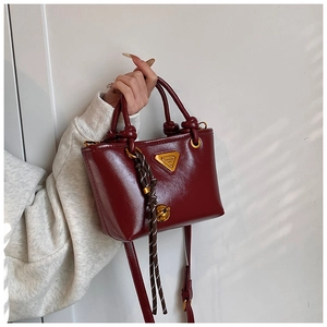 Détail du mini cabas en cuir bordeaux avec poignée nouée et logo en métal triangulaire