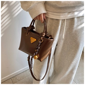 Détail du sac cabas en cuir marron avec poignée nouée et détail triangulaire métallique