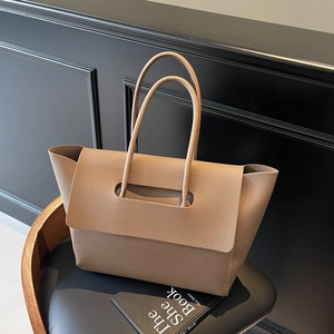 Large taupe lychee leather tote bag with long handles on a luxury leather chair