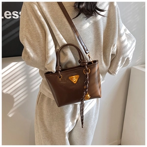 Détail d'un sac cabas en cuir marron avec garniture dorée et logo sur un mannequin