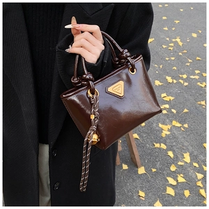 Détail d'un mini sac cabas en cuir verni marron foncé avec une poignée à nœud en corde
