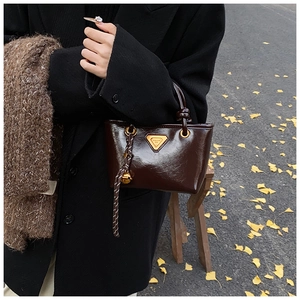 Détail d'un mini sac cabas vintage en cuir marron avec logo métallique et grelot doré