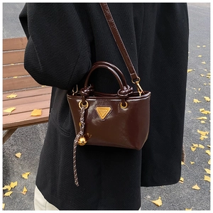 Détail du mini cabas en cuir verni marron foncé avec triangle doré et pendentif