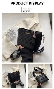 Détail du sac hobo matelassé noir avec large bandoulière à motif et logo doré élégant