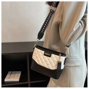 Close-up of quilted black and white crossbody bag with geometric wide strap and gold hardware
