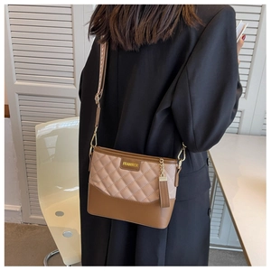 Close-up of quilted pattern leather bag with gold logo and wide printed shoulder strap