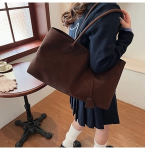 Detail of a large dark brown matte tote bag with minimalist shoulder strap and square tag