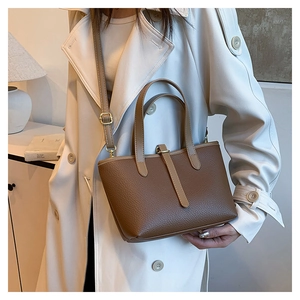 Macro shot of dark brown lychee-patterned soft leather tote bag on beige trench coat