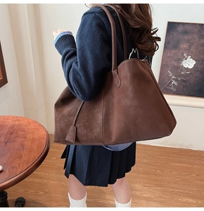 Detail of dark brown suede tote bag featuring large capacity and retro lock strap